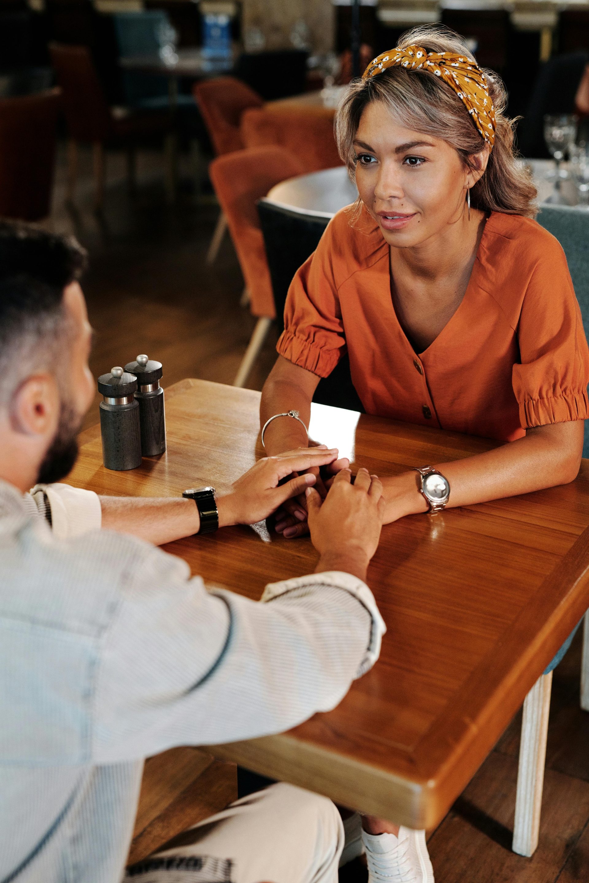 Couple holding hands and talking in a warm café setting, creating a romantic atmosphere.