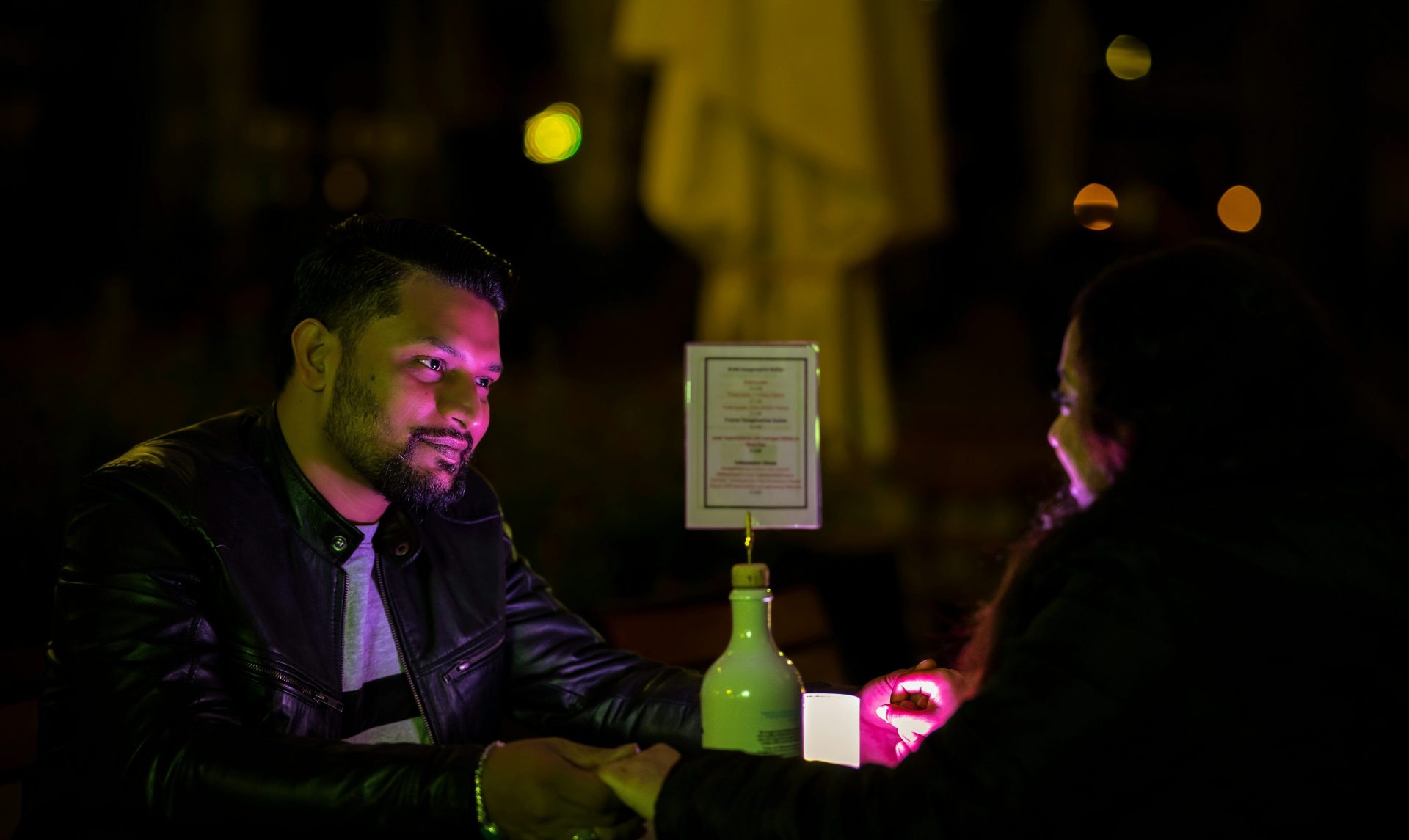 A man sitting at a table with a bottle of wine